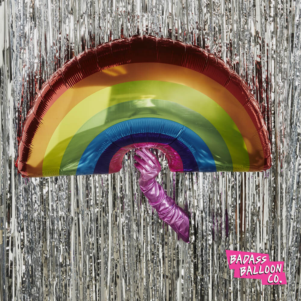 Giant rainbow-shaped balloon on a shiny silver background. Iconic funny balloons by Badass Balloon Co. 
