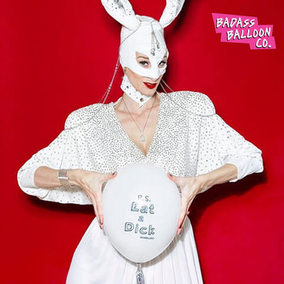 Beautiful model wearing a white bunny kinky outfit holding a balloon that reads "PS: Eat a Dick" - mature funny ballons by Baddass Balloon Co. 