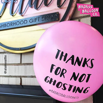 A pink inflated balloon with saying: Thanks For Not Ghosting standing in front of a gift shop. Funny balloons by Badass Balloon Co.